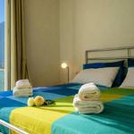 Schlafzimmer mit Blick auf See und Berge. Bett mit bunten Laken und Handtüchern.