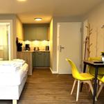 Schlafzimmer mit kleiner Küche und Essbereich mit gelben Stühlen.