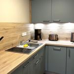 Küche mit Holz Arbeitsfläche, grauen Schränken und Küchengeräten.