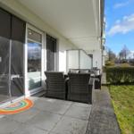 Terrasse mit Sitzgruppe und Glasfront. Regenbogenmuster vor Tür.