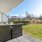 Terrasse mit Sitzgruppe und Blick auf Grünfläche und Bäume.