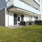 Terrasse mit Sitzgruppe und Garten vor modernem Haus