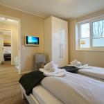 Zwei Betten mit weißen Laken und Handtüchern. Fenster mit Jalousie und Schrank.