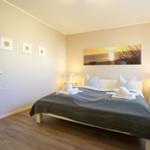 Schlafzimmer mit Bett, Nachttischen und Wandbild