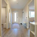 Flur mit Holzboden, Teppich und Türen zu Räumen. An der Wand hängen Haken und ein Spiegel.