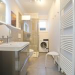 Badezimmer mit Dusche, Waschmaschine und Heizkörper