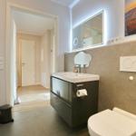 Bad mit Waschtisch, Toilette und Heizung. Spiegel und Wandbild sind sichtbar.