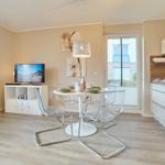 Wohn- und Essbereich mit Küche, TV und Essplatz.