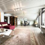 Wohn- und Essbereich mit rotem Sofa, Holzboden und Dachfenstern.