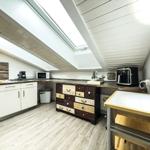 Küche mit Dachschrägen, Arbeitsplatte, Kühlschrank und Schrank.