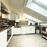 Küche mit weißen Schränken, Holzoptik und Dachfenster.