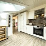 Küche mit weißen Schränken, Holzboden und Dunstabzug.