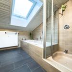 Badezimmer mit Dusche, Badewanne und Waschmaschine unter Dachschrägen.