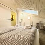 Zwei Betten mit karierten Bettdecken, Doppelwaschbecken und Aufbewahrungskörbe.