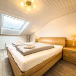 Schlafzimmer mit Dachfenster, Holzbett und Nachttisch mit Lampe.