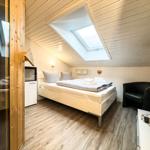 Schlafzimmer mit Dachschrägen, Dachfenster, Bett, Sessel und Schrank.