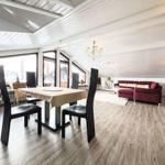 Essbereich mit Tisch und Stühlen, Wohnbereich mit rotem Sofa und Holzboden.