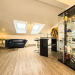 Wohnraum mit Sofa, Bar und Glasvitrine unter Dachschrägen.