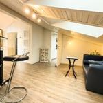 Wohnbereich mit Sofa, Tisch und Barhocker unter Holzdecke.