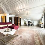 Wohn- und Essbereich mit rotem Sofa, Glas-Tisch und Holzboden.