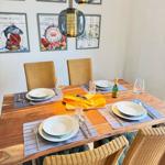 Wooden table with chairs, set with plates, cutlery, and bottle.