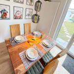 Dining room with wooden table, chairs, and wall art. Outside is a garden.