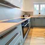 Kitchen with wooden surfaces, light cabinets, and modern cooktop.