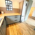 Kitchen with wooden floor, gray cabinets, and stainless steel refrigerator.