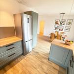 Kitchen with wooden floor, stainless steel refrigerator, and dining area with table and chairs.