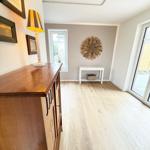 Entrance area with wooden floor, cabinet, table, and windows.