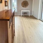 Bright entry hall with wooden floor, cabinet, and wall decoration.
