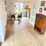 Entryway with wooden floor, dining area, and kitchen area.