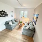 Living room with two sofas, wooden floor, and window. Wall decor and table.