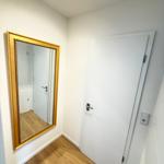 Hallway with gold-framed mirror and white door with metal handle