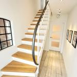 Staircase with wooden steps, white railings, and floor. Pictures hang on the wall.