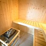 Sauna with wooden walls, bench, and stone heater.
