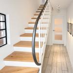 Stairs with wooden steps and white railing lead upstairs. Hallway with wooden flooring and door.