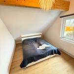 Bedroom with sloped ceiling, wooden floor, and bed with dark bedding.