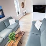 Living room with two sofas, wooden table, and TV on the wall.