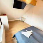 Bedroom with bed, TV, and wooden floor