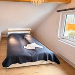 Bedroom with sloped ceiling, bed, window, and wooden beam.