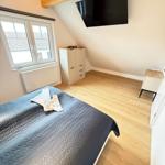 Bedroom with sloped ceiling, bed, wardrobe, and wall-mounted TV.