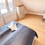 Bedroom with sloped ceiling, bed, wardrobe, and TV.