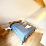 Bedroom with wooden floor, bed, and wooden beam on ceiling.