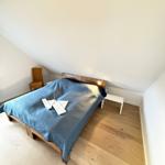 Bedroom with wooden floor, bed, and nightstand