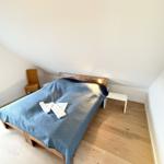 Bedroom with bed, nightstand, and chair under sloped ceiling