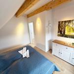 Bedroom with wooden beams, bed, and dresser.