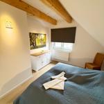 Bedroom with sloped ceiling, bed, dresser, and window.