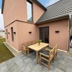 Terrace with wooden table and chairs in front of a house with pink facade.