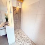 Shower with wooden wall, sink and mosaic floor